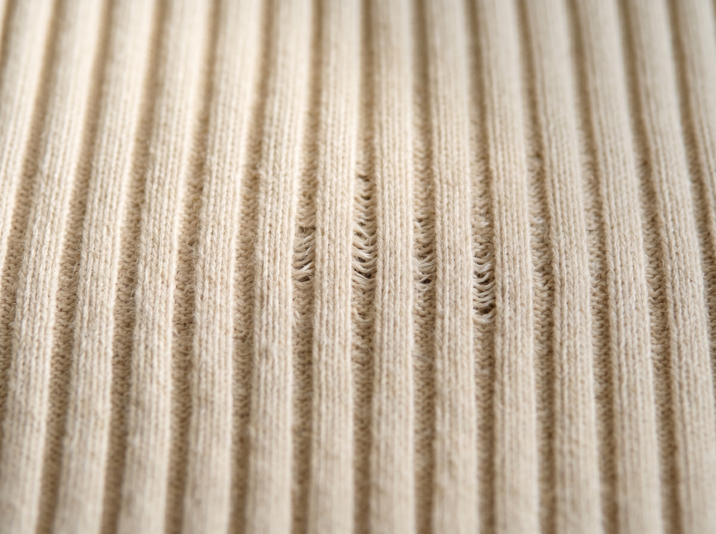 Close-up of oat-cream cotton rib knit fabric.